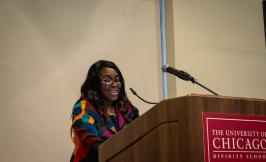 Patricia Posey standing in front of a UChicago podium speaking.